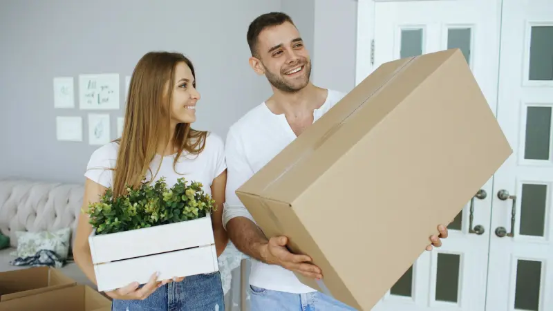 Umzugskarton wird in die neue Wohnung getragen – Möbeltaxi